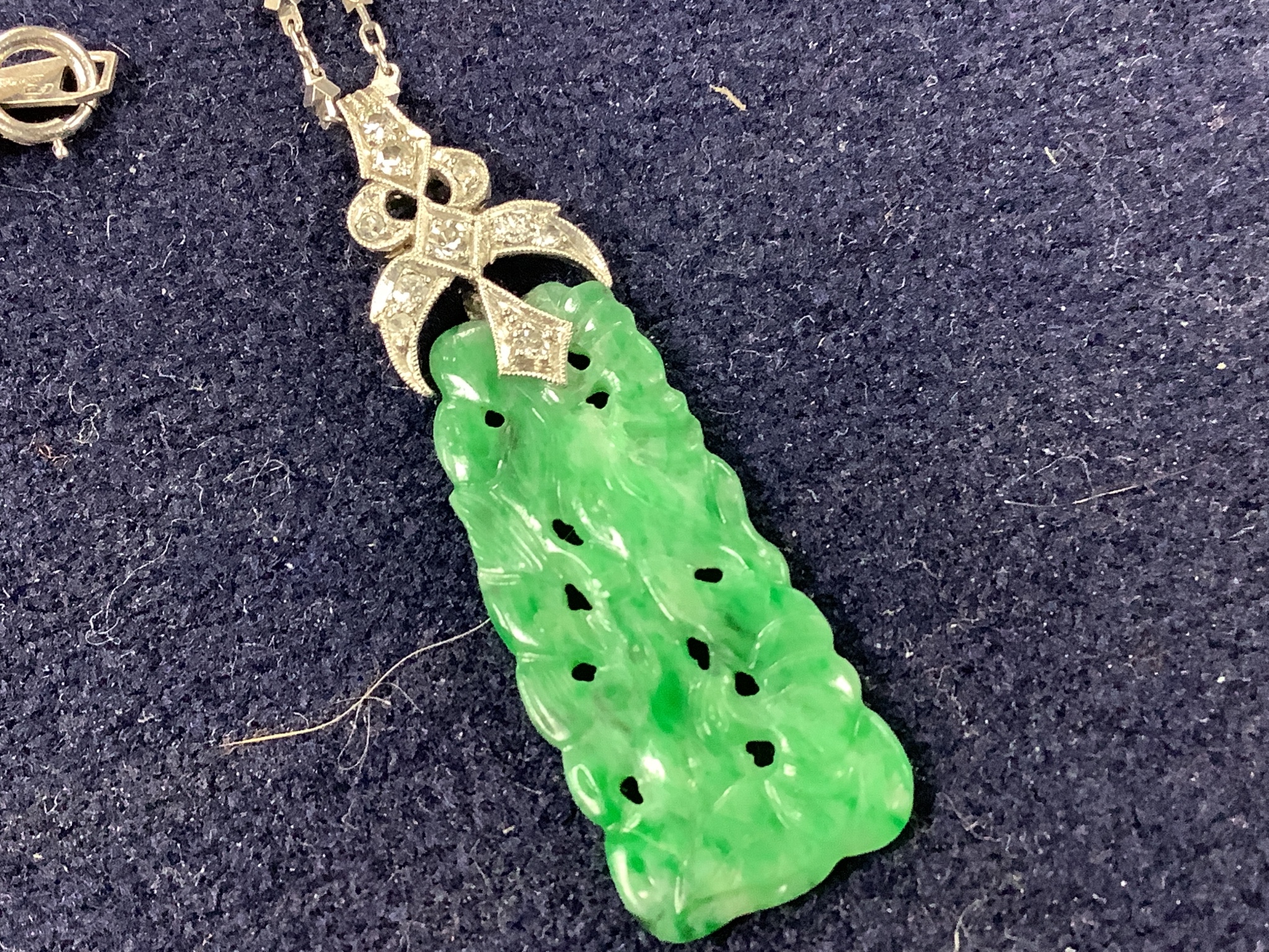 A 1920's white metal and diamond mounted carved jade pendant, numbered 'G 320 1', 4cm, on a platinum fancy link chain, 40cm, gross weight 7.6 grams